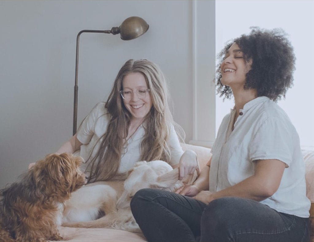 Women laughing on couch with a dog