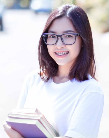 young girl smiling with braces holding books